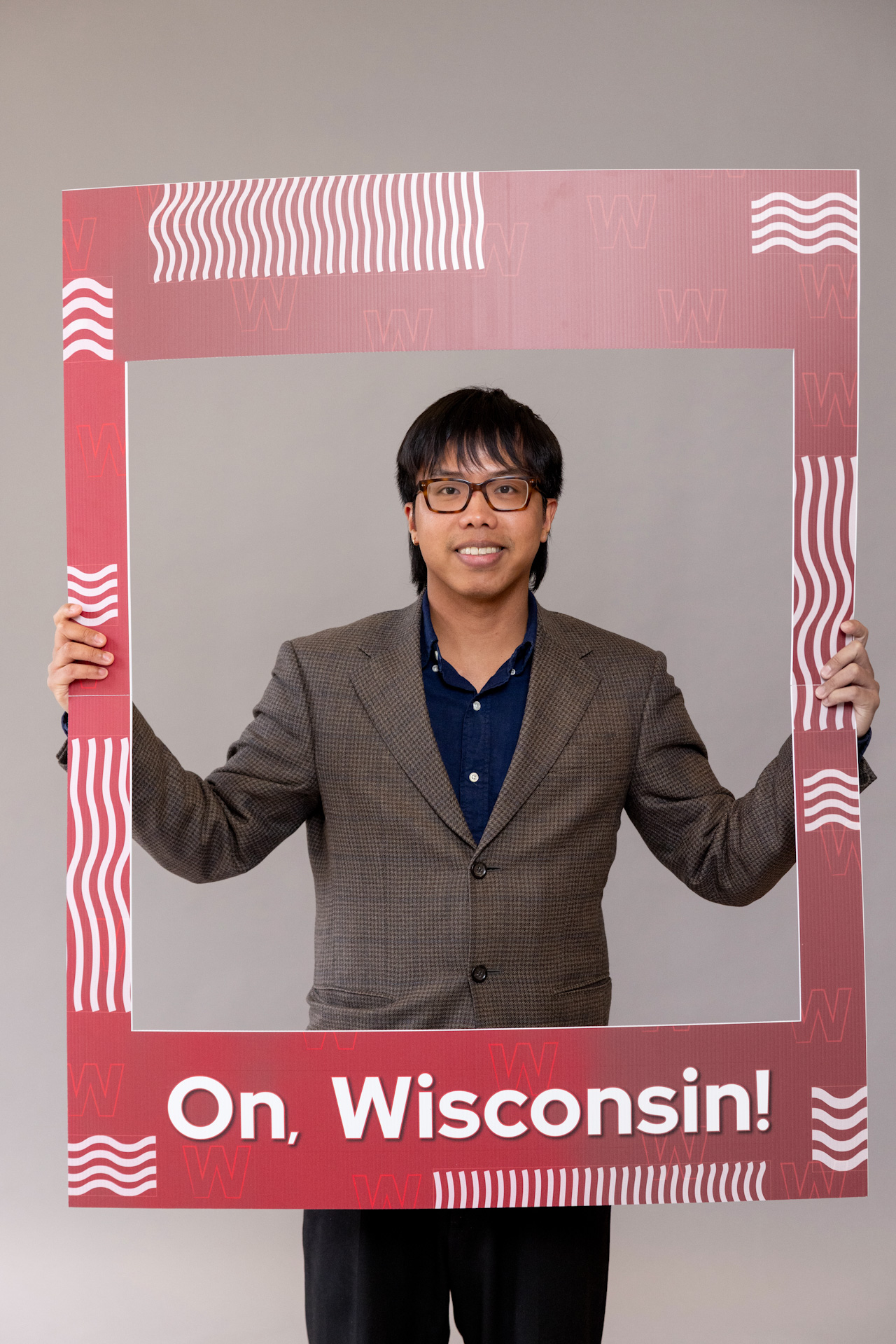 Returning adult student holding a frame that reads, "On, Wisconsin."